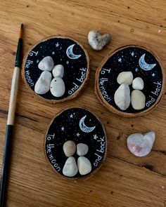 three small rocks are sitting on a wooden table next to a paintbrush and pencil