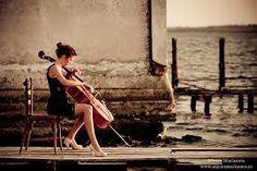 a woman playing the violin on a dock