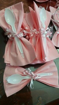 four pink napkins with spoons and forks in them sitting on a glass table