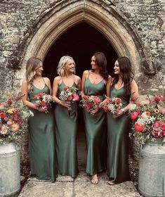 bridesmaids in green dresses standing outside an old stone building with their bouquets