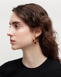 a woman with long brown hair wearing large wooden earring in front of her face