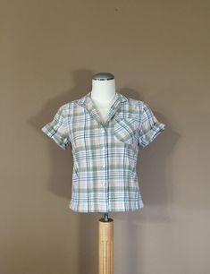 Authentic vintage short sleeve shirt. Has collar with full button up front. Dates from late 80's to early 90's. Classic plaid design. Soft cotton blend. Shorter cropped style. This shirt is in great condition with little to average signs of previous use. Still has many years of wear left. Check out my shop 'TheBarnLadder' for reviews and feedback All items are free of rips, tears, holes, and stains. Vintage items are subject to signs of previous wear. Purchase Policy All vintage items are non re Cheap Vintage Cotton Shirt, 90s Short Sleeve Tops With Button Closure, Retro Plaid Short Sleeve Blouse, Retro Plaid Short Sleeve Shirt, Retro Short Sleeve Plaid Blouse, Retro Short Sleeve Plaid Shirt, Retro Plaid Short Sleeve Tops, Vintage Plaid Short Sleeve Shirt, Plaid Vintage Short Sleeve Shirt