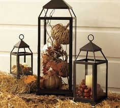 three lanterns sitting on top of hay next to each other