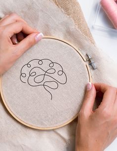 a woman is working on a cross - stitch project with her hands and sewing needles