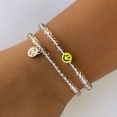 two bracelets with smiley face charms on each one, both in silver and yellow