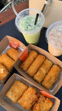 two boxes filled with food sitting on top of a table next to cups and drinks