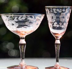 two glass goblets sitting next to each other on a table