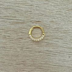 a gold nose ring with three small white stones