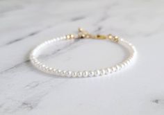 This gorgeous and dainty bracelet is made from natural pure white and high luster AAA grade freshwater seed pearls. If you're searching for a strand of high quality pearls that'll add elegance into your bracelet stack, this is the one for you! The size of the pearls are only around 3mm, extremely dainty and can be worn alone for a minimalist look too. Sterling silver, gold filled and rose gold filled finish options are available for your choosing. 14k solid yellow gold also available, but no ext White Minimalist Bracelets For Anniversary, Delicate White Bracelet For Anniversary, Minimalist White Bracelets For Anniversary, Delicate White Pearl Bracelet For Anniversary, Dainty White Beaded Bracelets For Formal Occasions, White Dainty Beaded Bracelets For Formal Occasions, White Gold Bracelet With Pearl Charm For Wedding, Minimalist White Pearl Bracelet For Anniversary, White Adjustable Gold Bracelet For Anniversary