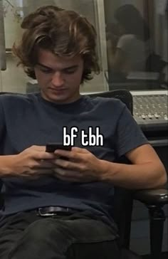 a man sitting in a chair looking at his cell phone with the words b f tbh on it