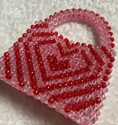 a pink and red heart shaped beaded brooch on a white surface with the word love spelled out