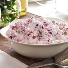 a white bowl filled with fruit salad sitting on top of a wooden table next to a knife