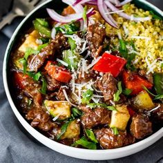 a white bowl filled with meat and veggies on top of a blue table cloth