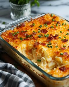 a casserole dish with cheese, bacon and green onions in it on a table