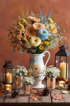 a vase filled with lots of flowers sitting on top of a table next to candles