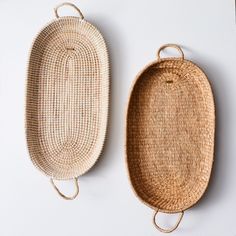 two woven baskets sitting next to each other on top of a white surface with handles