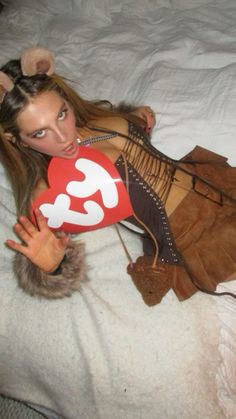 a woman laying on top of a bed holding a red heart shaped pillow in her hand