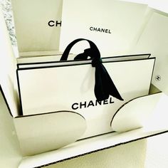 an open chanel bag sitting on top of a white box with black ribbon around it