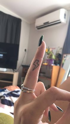 a woman's finger with a small lightning tattoo on her left hand and a ring on the middle finger