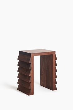 a small wooden table with four sections stacked on top of each other, in front of a white background