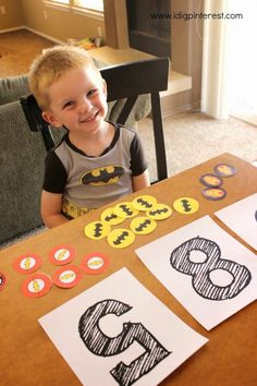 a young boy sitting at a table in front of some paper cut outs with numbers on them