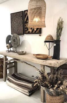 a wooden table topped with lots of baskets and vases filled with plants next to lamps