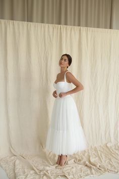 a woman in a white dress poses for the camera