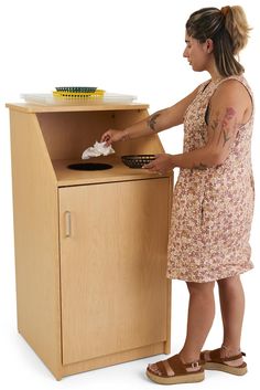 a woman standing in front of a wooden cabinet with a pan on top of it