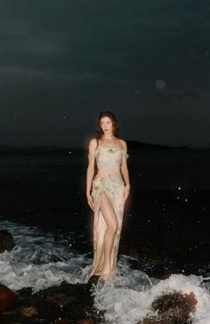 a woman standing in the ocean at night with her body covered by water and rocks