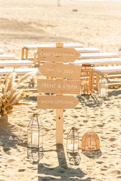 a wooden sign sitting on top of a sandy beach next to a birdcage