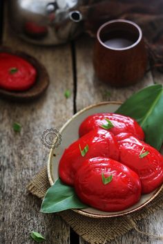 a bowl filled with red fruit sitting on top of a wooden table