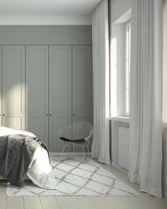 a bed room with a neatly made bed next to a white chair and a window