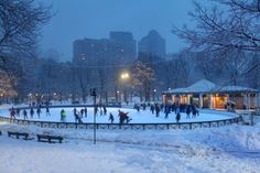 people skating on an ice rink in the city at night with buildings in the background