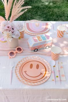 a table topped with plates and cups filled with food next to a flower vase on top of a white table cloth