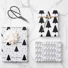 wrapping paper and scissors on a white marble countertop with black and white christmas trees