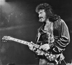 an old black and white photo of a man with a guitar in his hand on stage