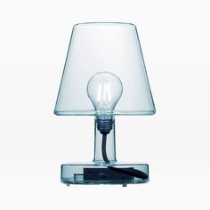 a table lamp with a glass shade on the base and a black cord plugged into it