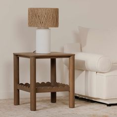 a small table with a lamp on it next to a white couch in a living room