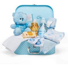 a blue teddy bear sitting on top of a suitcase filled with baby goods and personal care items