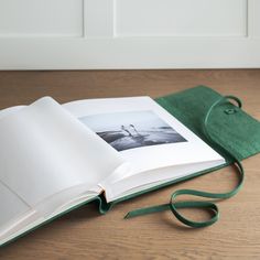 an open book sitting on top of a wooden table next to a green cloth bag