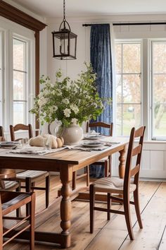 a dining room table with chairs and a vase filled with flowers