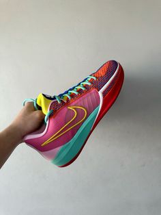 a person holding up a pair of colorful shoes