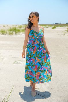 Get ready for your next summer vacay with our Blue Lagoon Dress! This midi dress features a beautiful tropical print in vibrant hues, complete with tropical leaf and bird motifs. The sweetheart neckline adds a flirty touch, while the adjustable spaghetti straps, shirred elastic waistline, and ruffled skirt provide a flattering silhouette. Get your paradise vibes on with this fun dress. It is fully lined and fits true to size. 80% Rayon, 15% Linen, 5% Cotton Brand- By The River Model is 5'5" and Summer Tropical Print Midi Sundress, Summer Midi Sundress With Tropical Print, Tropical Floral Print Midi Dress For Beach Season, Tropical Floral Print Midi Dress For Beach, Tropical Floral Print Sundress For Vacation, Sleeveless Tropical Print Midi Dress For Beach, Blue Tropical Print Maxi Dress For Beach Party, Tropical Multicolor Midi Dress For The Beach, Blue Tropical Print Dress For Vacation