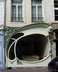 a car is parked in front of a building with an arched window and ornate decoration