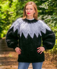 a woman standing in the woods wearing a black and white sweater