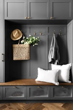 a bench with some pillows and a hat on it next to a wall mounted coat rack