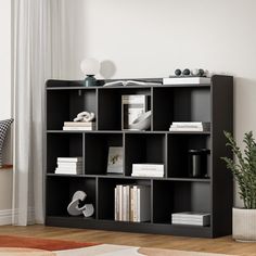 a black book shelf with books on it in a living room next to a window