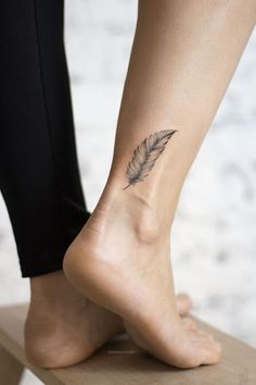 a woman's foot with a feather tattoo on it