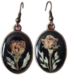 the earrings are decorated with flowers and leaves on black glass, which is hanging from silver hooks