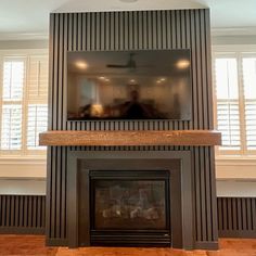 a living room with a fire place in the center and two people sitting on the other side